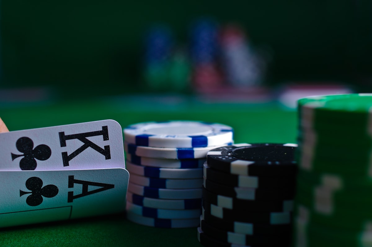 Tangan memegang kartu poker di samping tumpukan chip